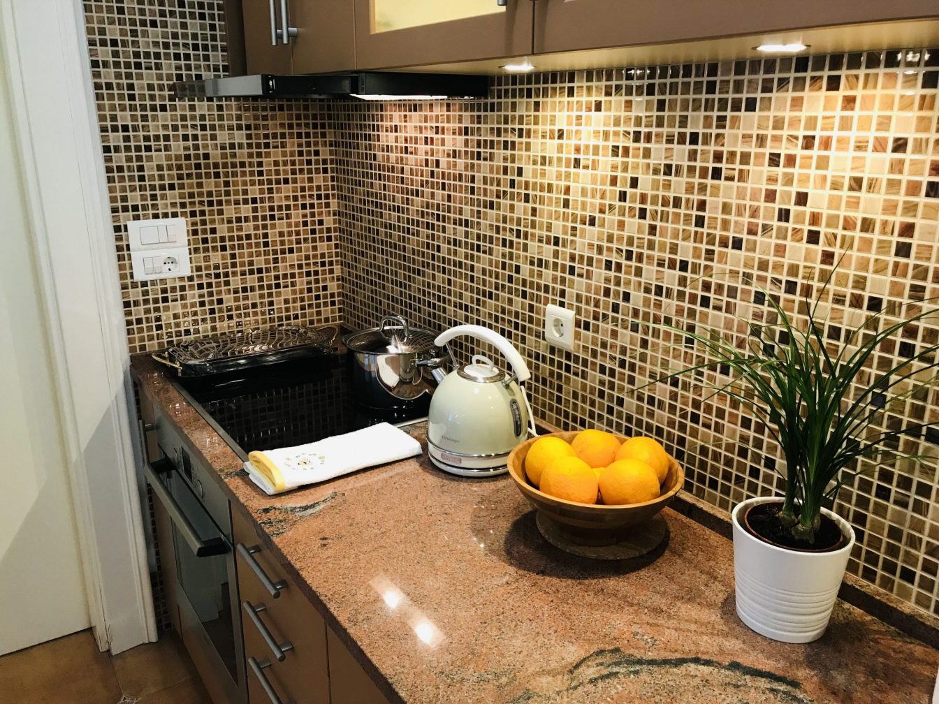 Large ktichen with small-tiled walls and appliances.