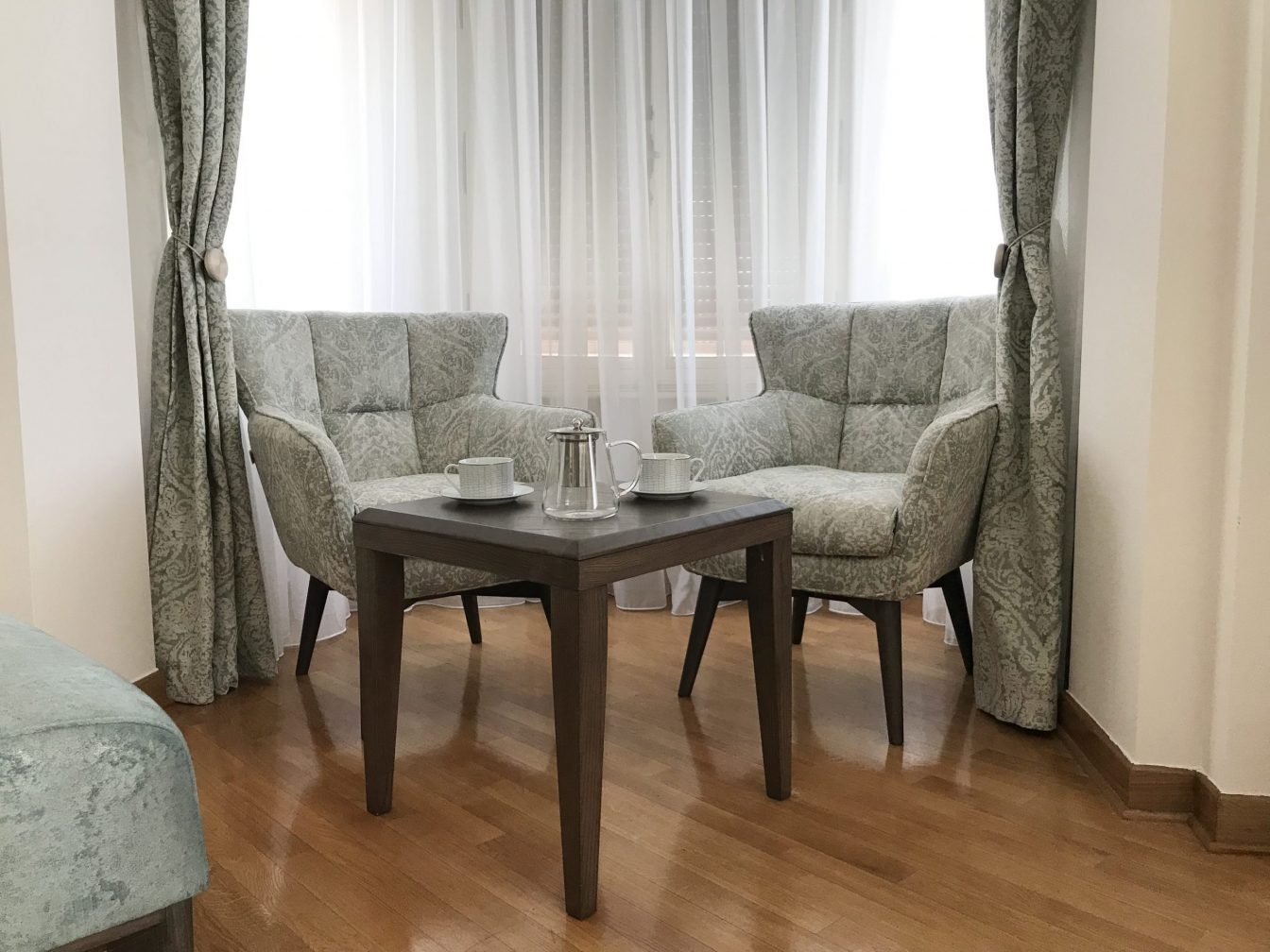 Two sofas with a small table in the corner of a room in front of a window